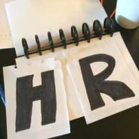 Photo of piece of torn paper with letters showing HR torn down middle on HRExaminer.com
