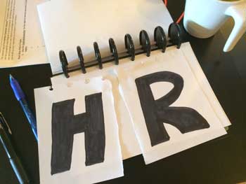 Photo of piece of torn paper with letters showing HR torn down middle on HRExaminer.com