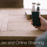 photo of person holding or looking at iphone with hand resting on table in feature photo for HRExaminer.com v6.12 for March 27, 2015